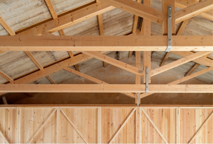 La charpente apparente support la toiture dont la sous-face est réalisée en planches de coffrages de réemploi. ©️Milena Villalba<br/> Crédit photo : dr -