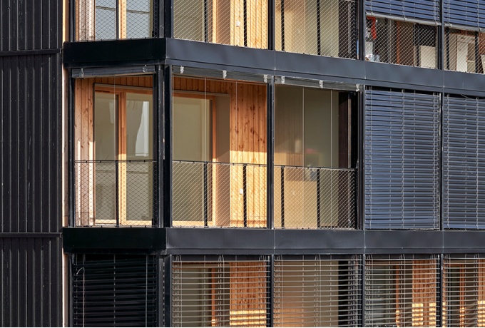 La grille reçoit les protections solaires au nu extérieur de bâtiment. Elles rendent appropriables les coursives en été.<br/> Crédit photo : DENANCÉ Michel