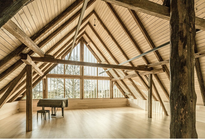 La salle de répétition s’installe sous les combles. Le nouveau pignon entièrement vitré la baigne de lumière naturelle et met en valeur la charpente de l’édifice.<br/> Crédit photo : Artbuild .