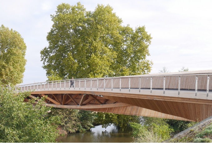 La passerelle sur le Renaison surprend autant par sa finesse, relativement à sa portée, que par le «mystère» de sa structure, en grande partie masquée par un carrelet de douglas.<br/> Crédit photo : © Arborescence  